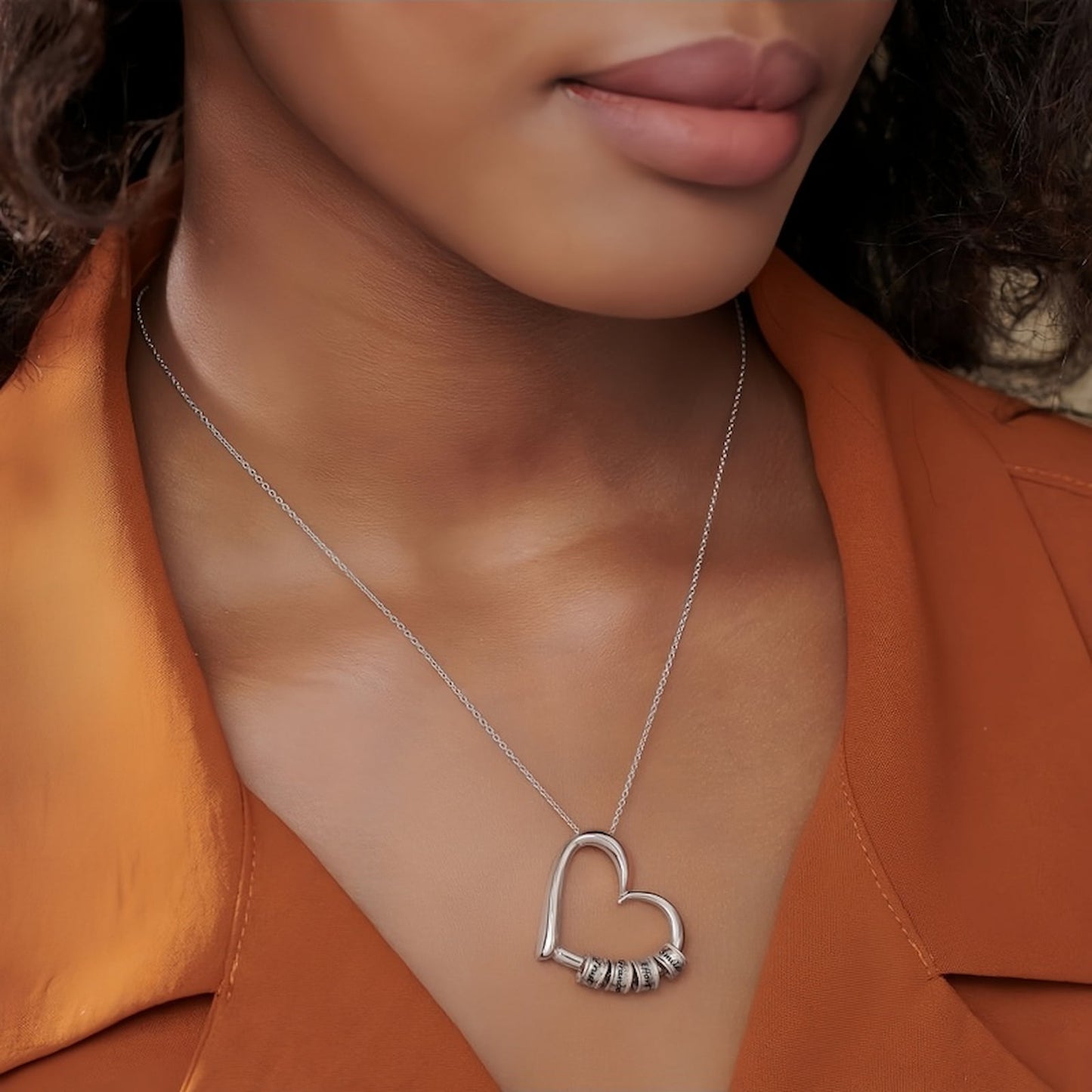 Close-up of a model wearing the personalized sterling silver heart necklace with engraved stacking charms, showcasing the fit and look.