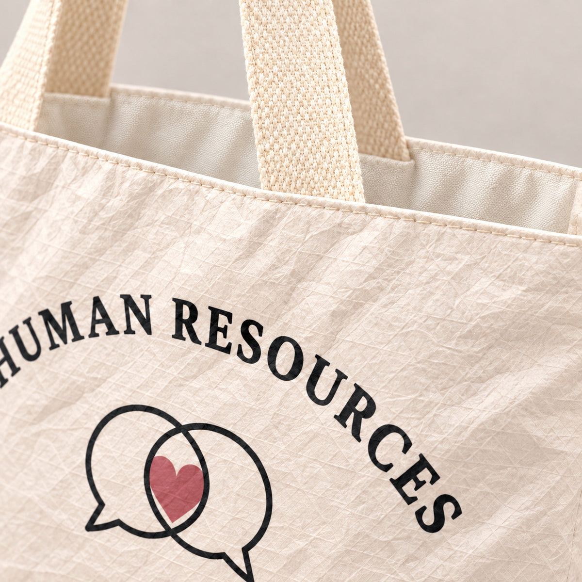 Close-up of the cream Human Resources tote showing its crinkled texture and woven handle.