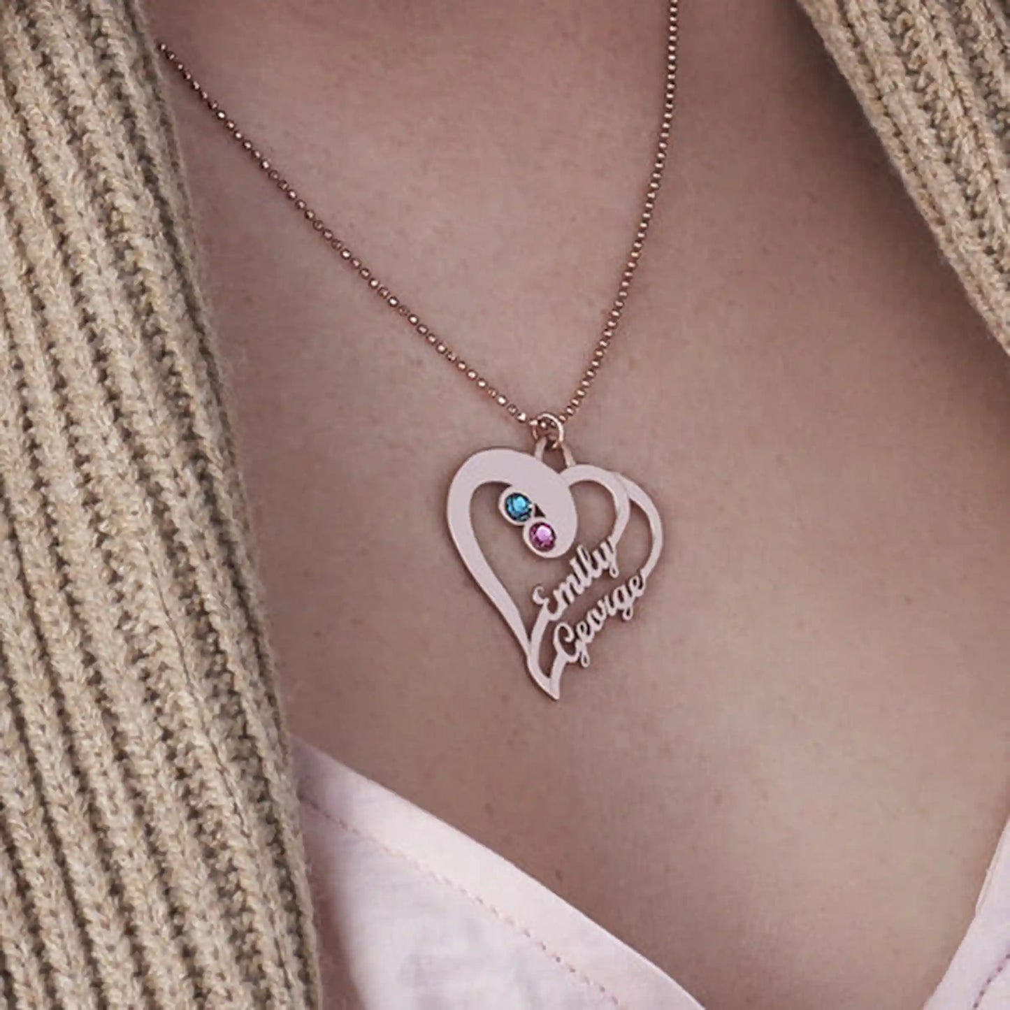 Close-up of personalized intertwined heart pendant featuring two colored birthstones and script names