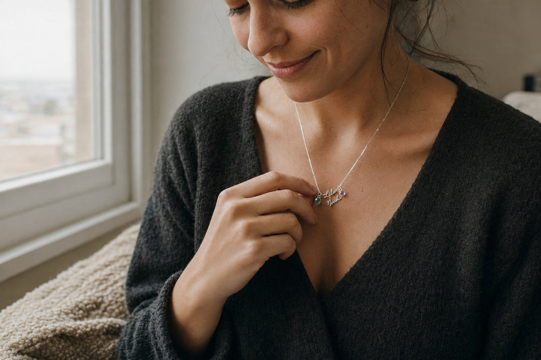 Woman holding a personalized name necklace with birthstones by a softly lit window