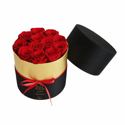 Elegant woman holding a black and gold box of forever red preserved roses.