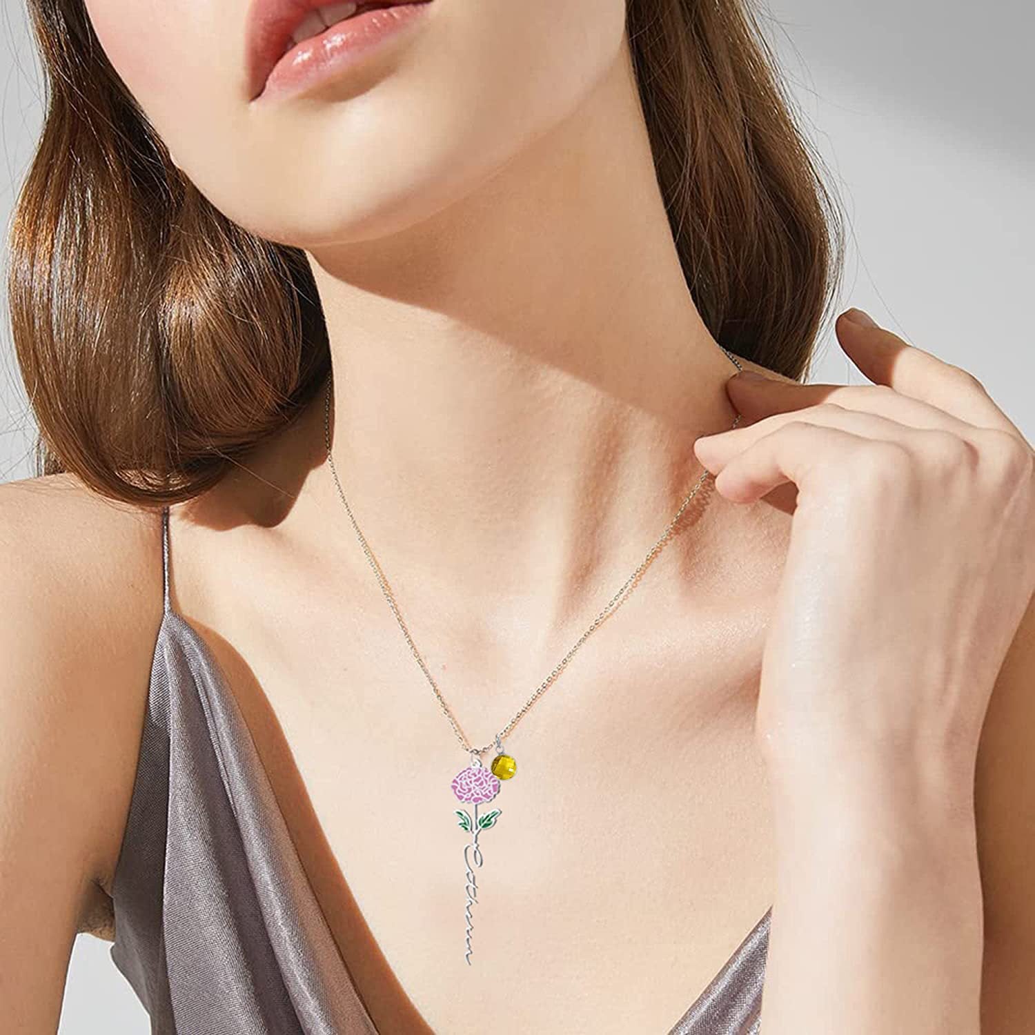 Silver carnation floral name necklace with yellow birthstone worn by a model.
