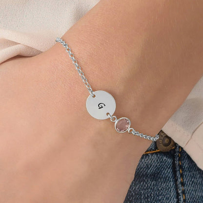 Close-up engraved initial coin bracelet. Sterling silver disc with letter G & gemstone.