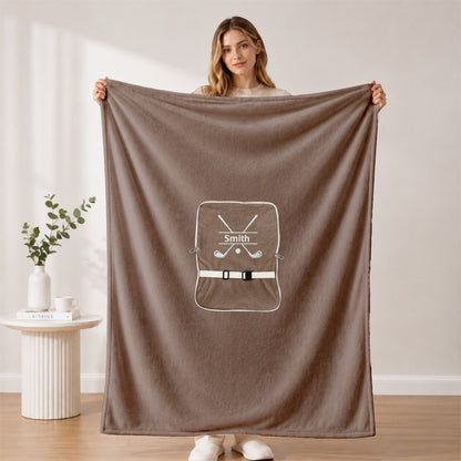 Woman holding open dark green golf-themed blanket.