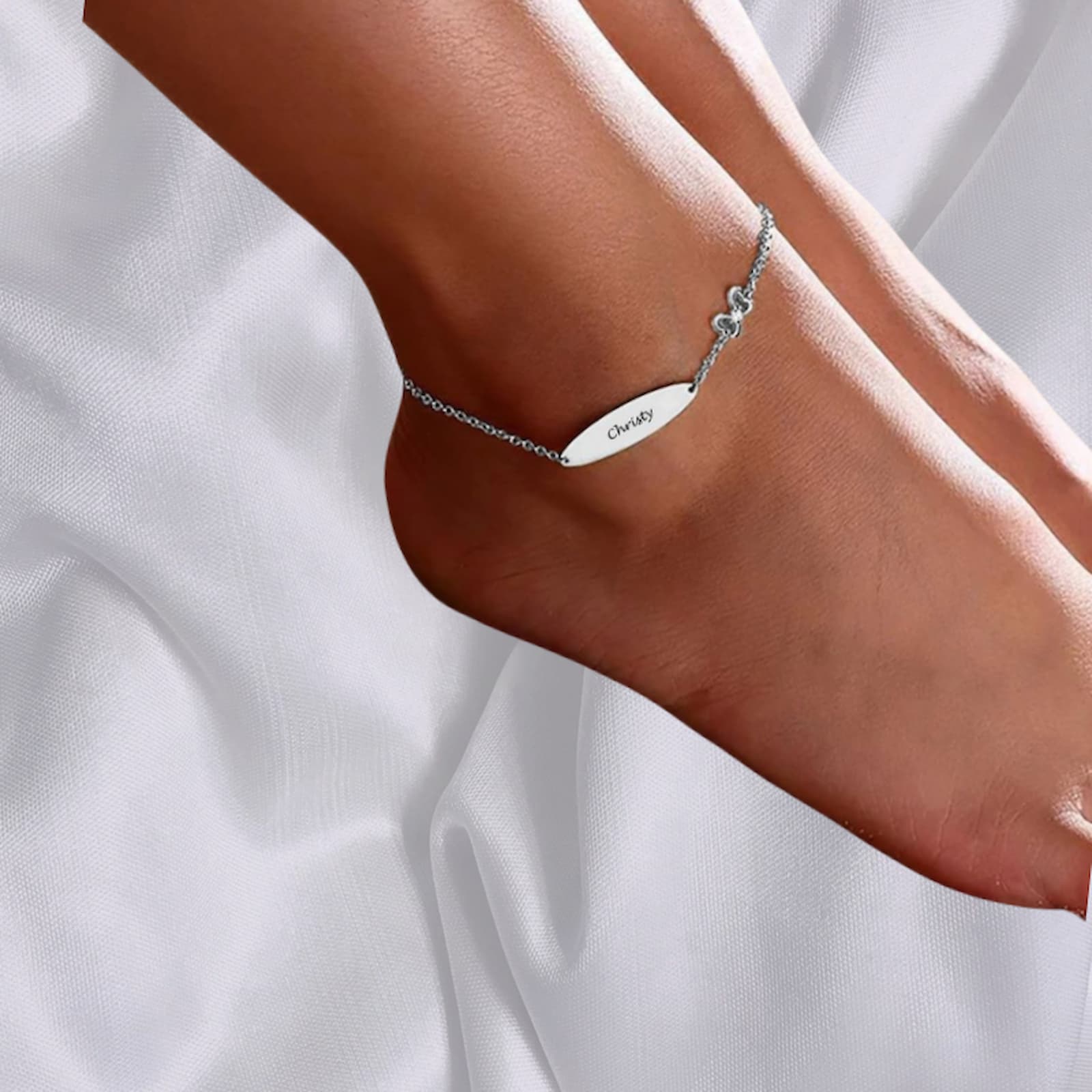 Custom engraved sterling silver name anklet/bracelet shown worn on a woman's ankle/foot.
