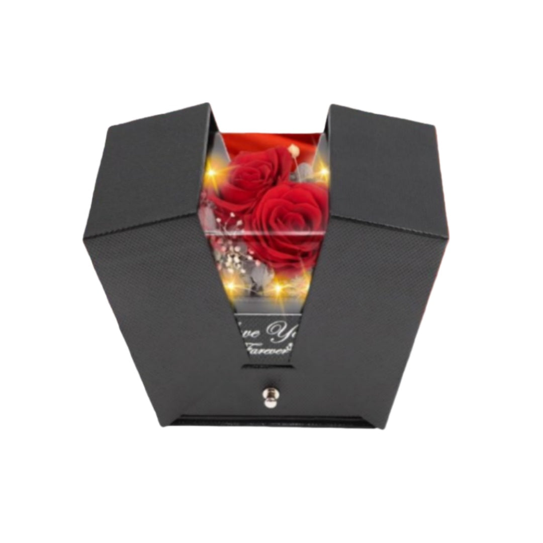 Half-open black jewelry gift box featuring a glowing preserved red rose inside.