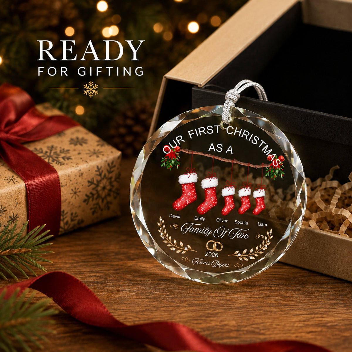 Gift-ready personalized family Christmas ornament beside an open gift box with ribbon and Christmas decor