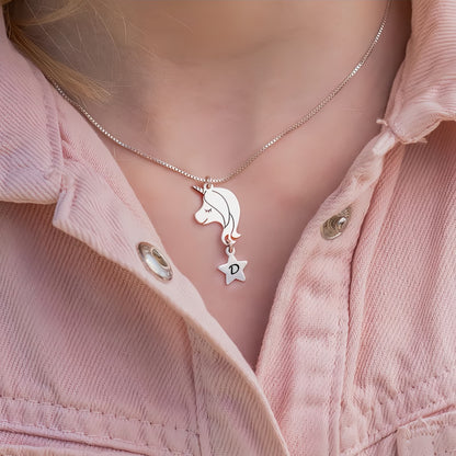 Close-up of a young girl wearing the silver personalized unicorn initial necklace on a pink jacket, showing the perfect size.