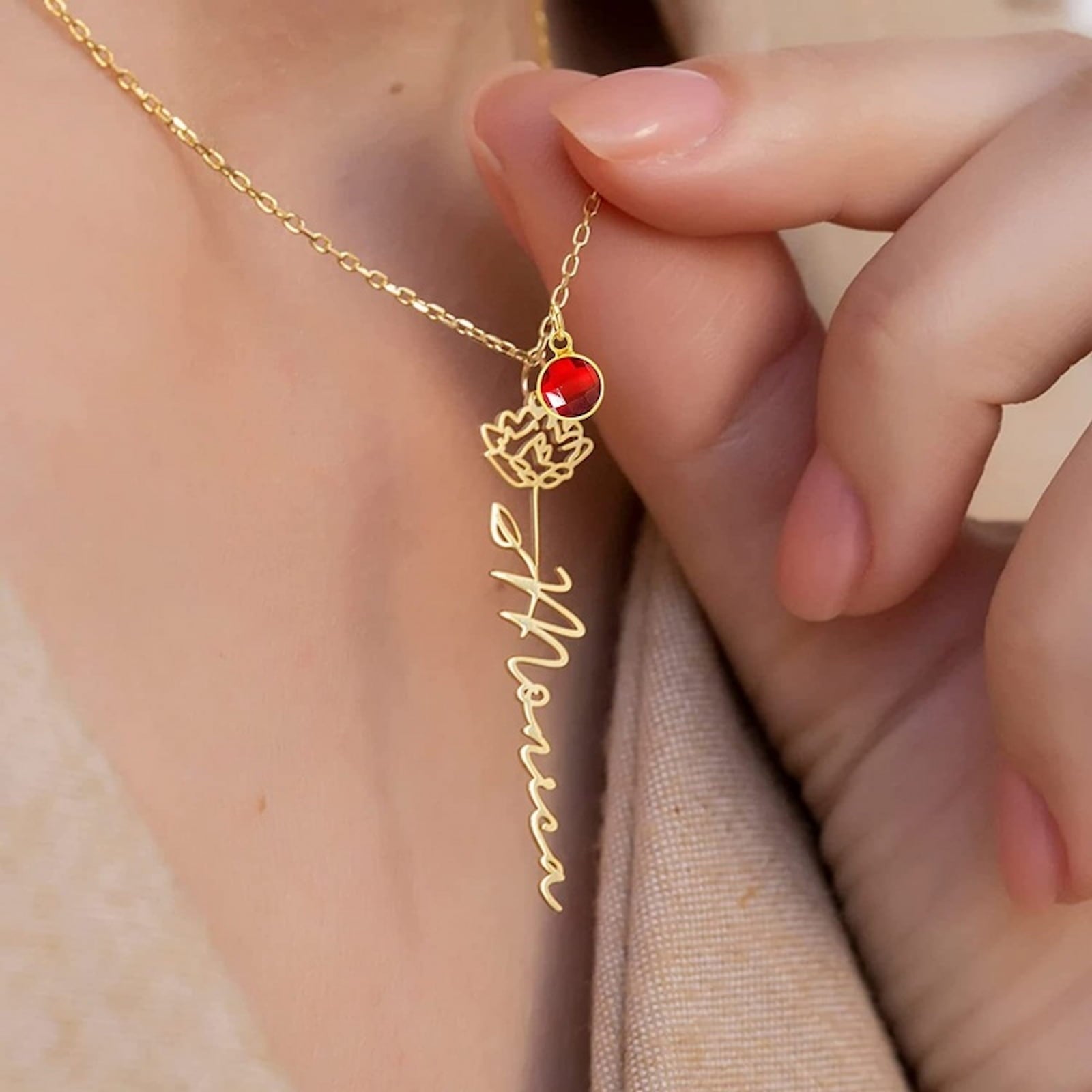 Gold Monica name necklace with carnation flower and red birthstone.