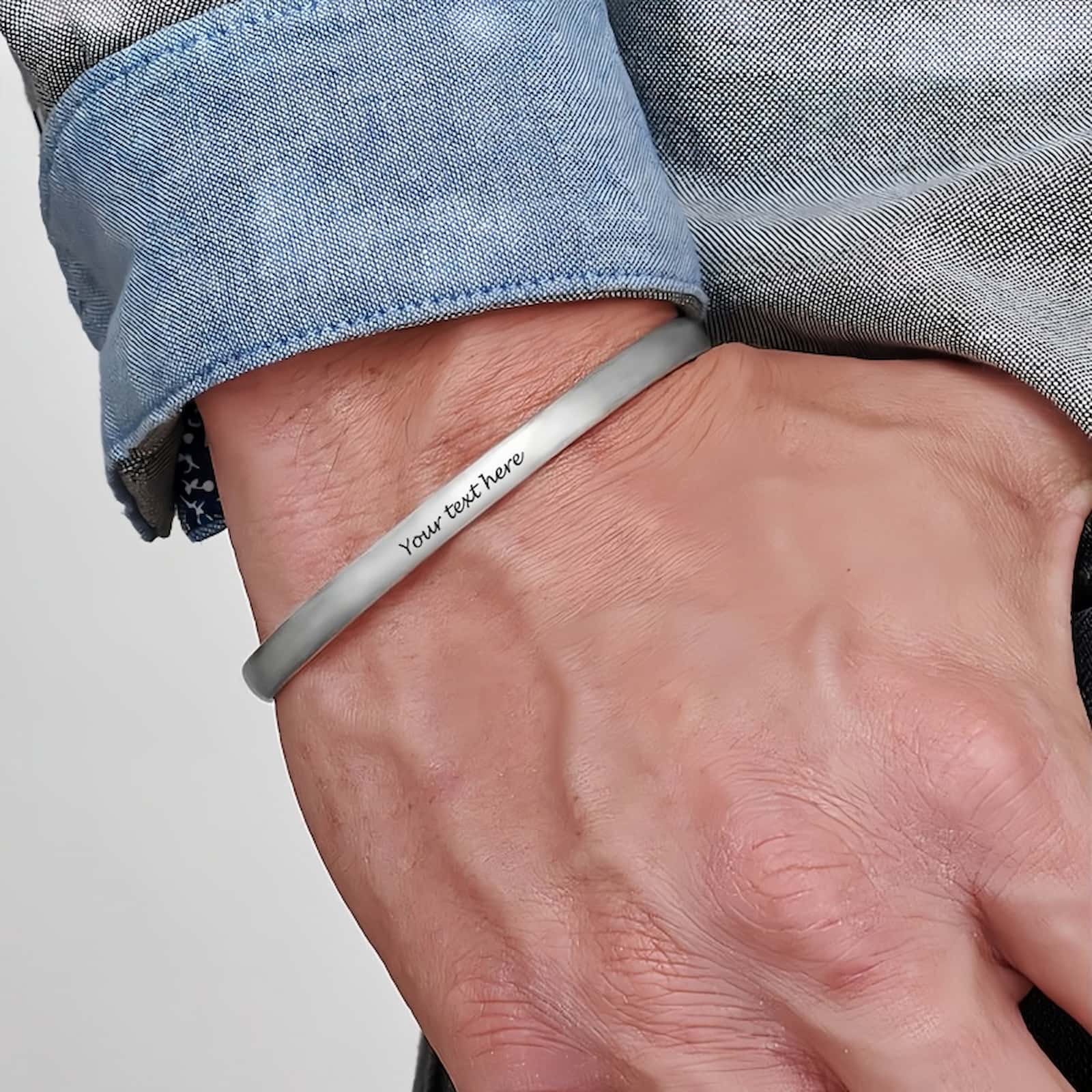 Man wearing custom engraved silver cuff bangle bracelet with personalized text.