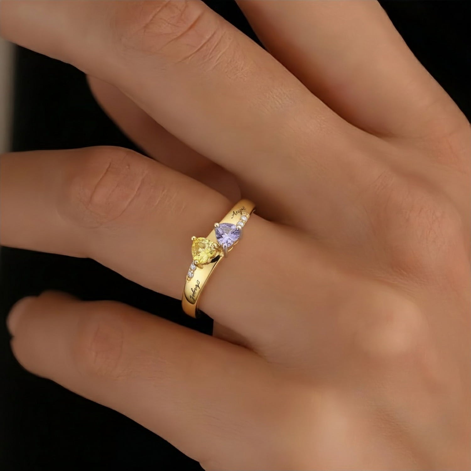 Model wearing custom yellow gold double heart birthstone ring on middle finger.