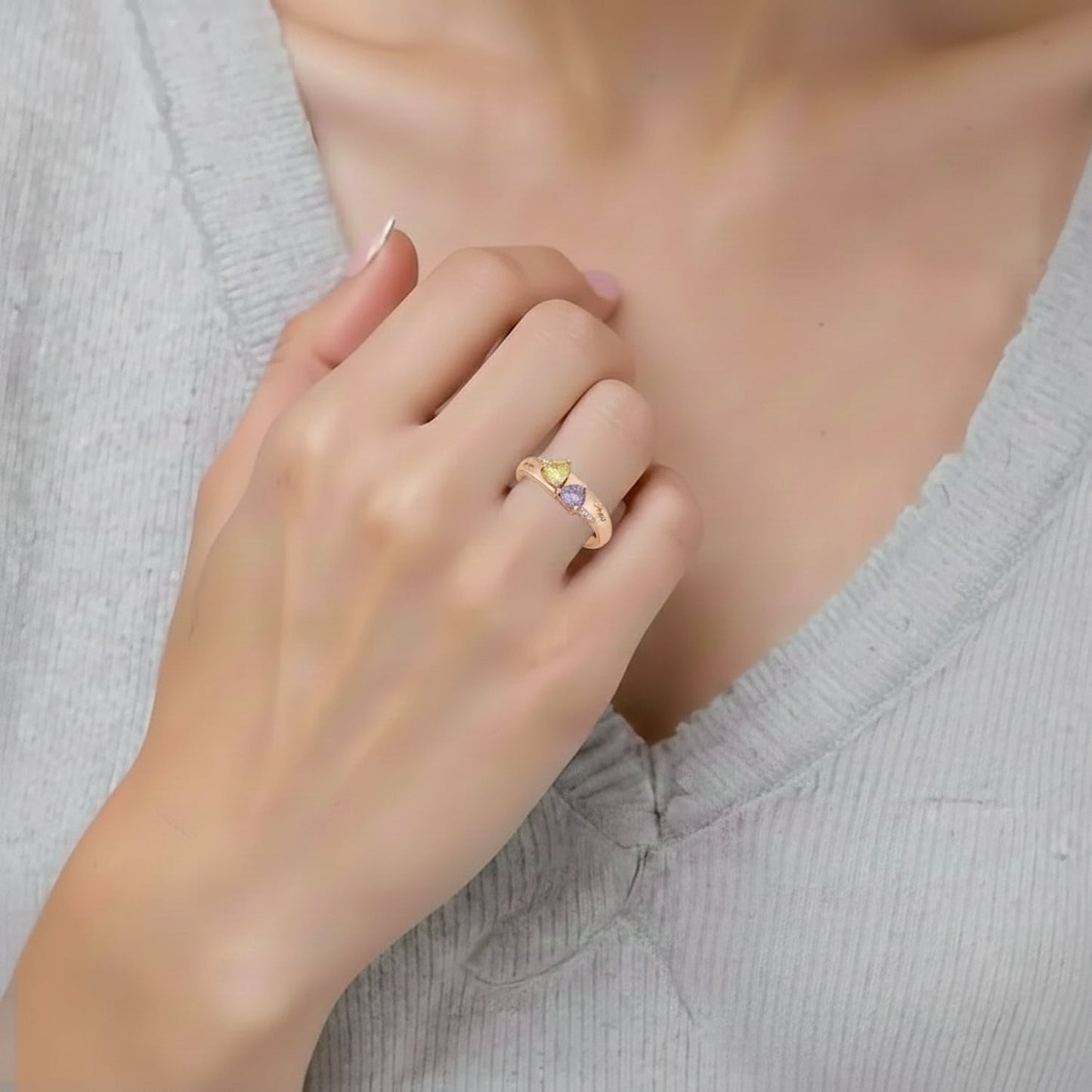 Model wearing personalized rose gold heart ring with purple and yellow gems.