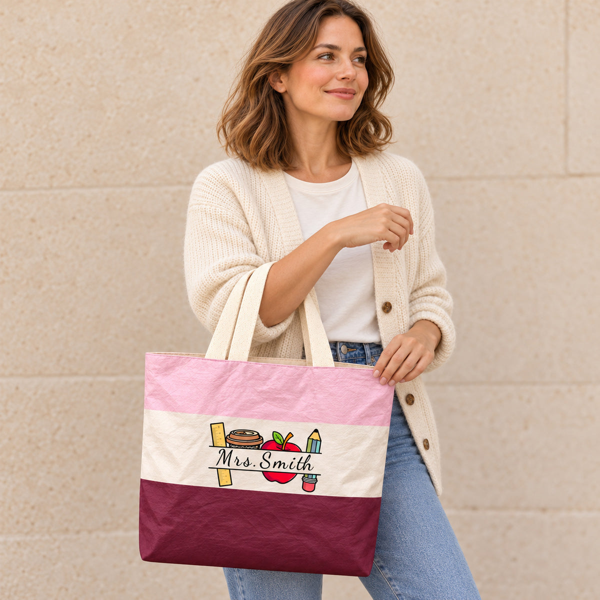 Woman carrying the Mrs. Smith colorblock teacher tote on her bent forearm with both cream handles.
