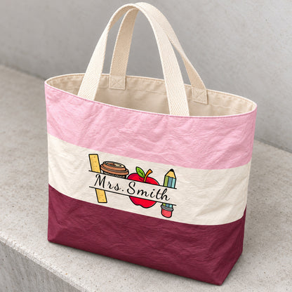 Angled detail of the crinkled colorblock teacher tote, cream canvas lining, woven handles and Mrs. Smith print.