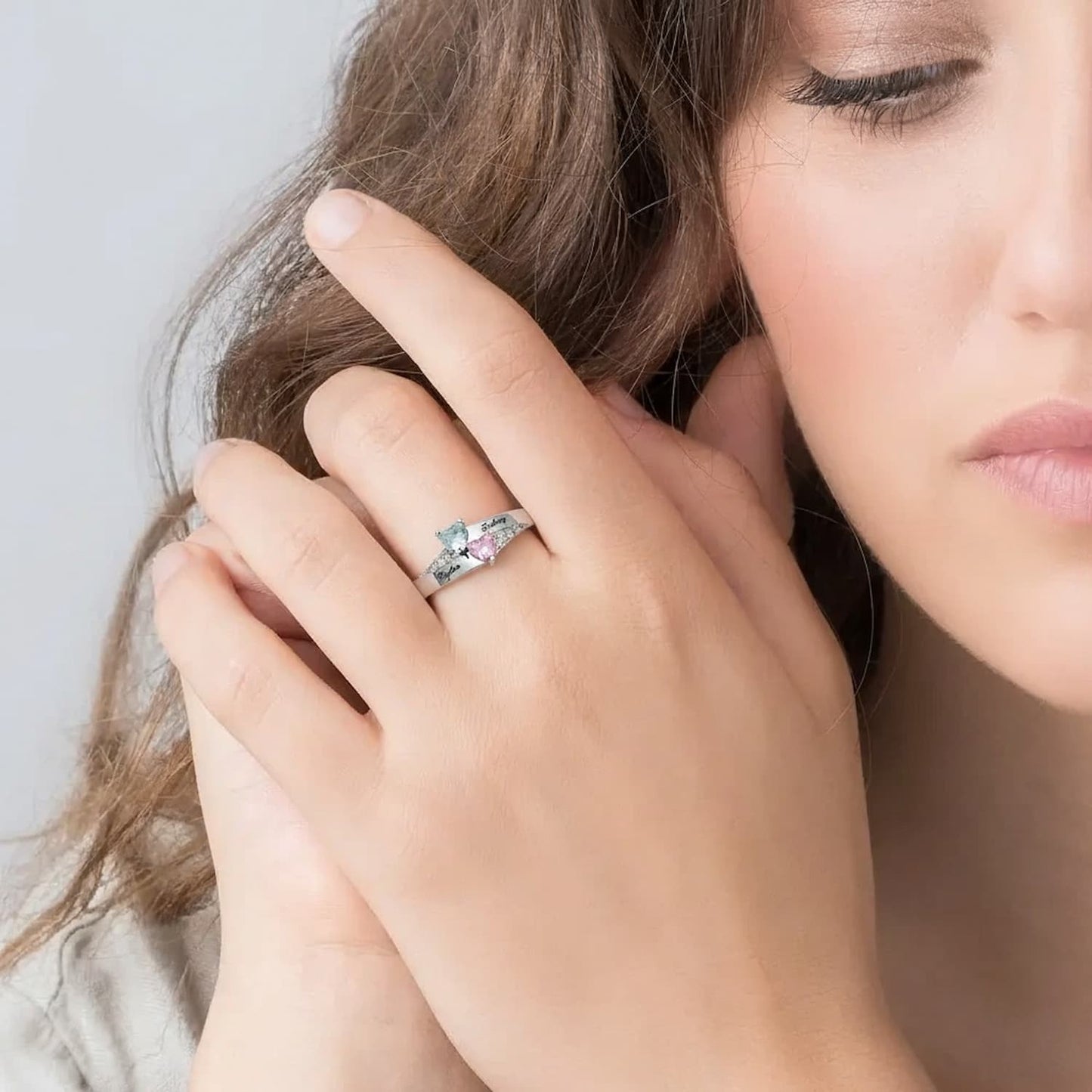 Custom sterling silver double heart birthstone ring worn on female hand.