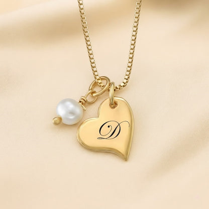 Detailed close-up shot of a personalized gold heart initial necklace with a pearl pendant.