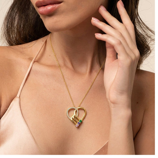 A woman wearing a custom heart necklace with birthstones.