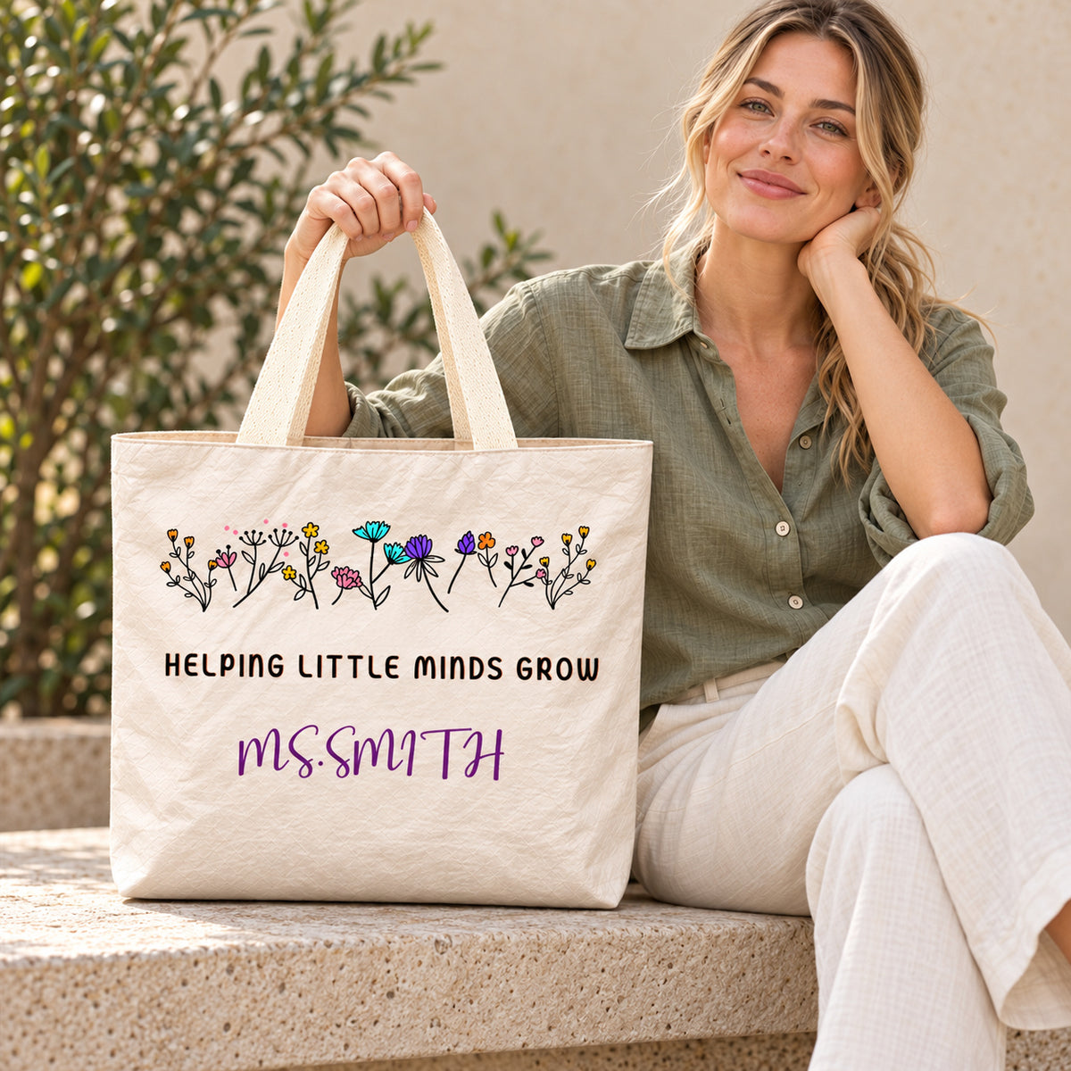 Personalized helping little minds grow teacher tote bag with custom name, showing the crinkled paper-like surface and handles.
