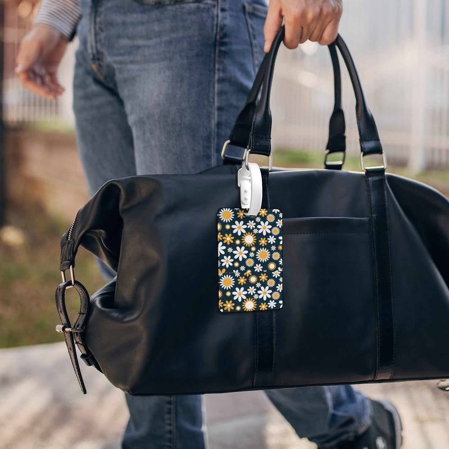 Personalized Daisy Bag Tag on a traveler's black duffel bag.