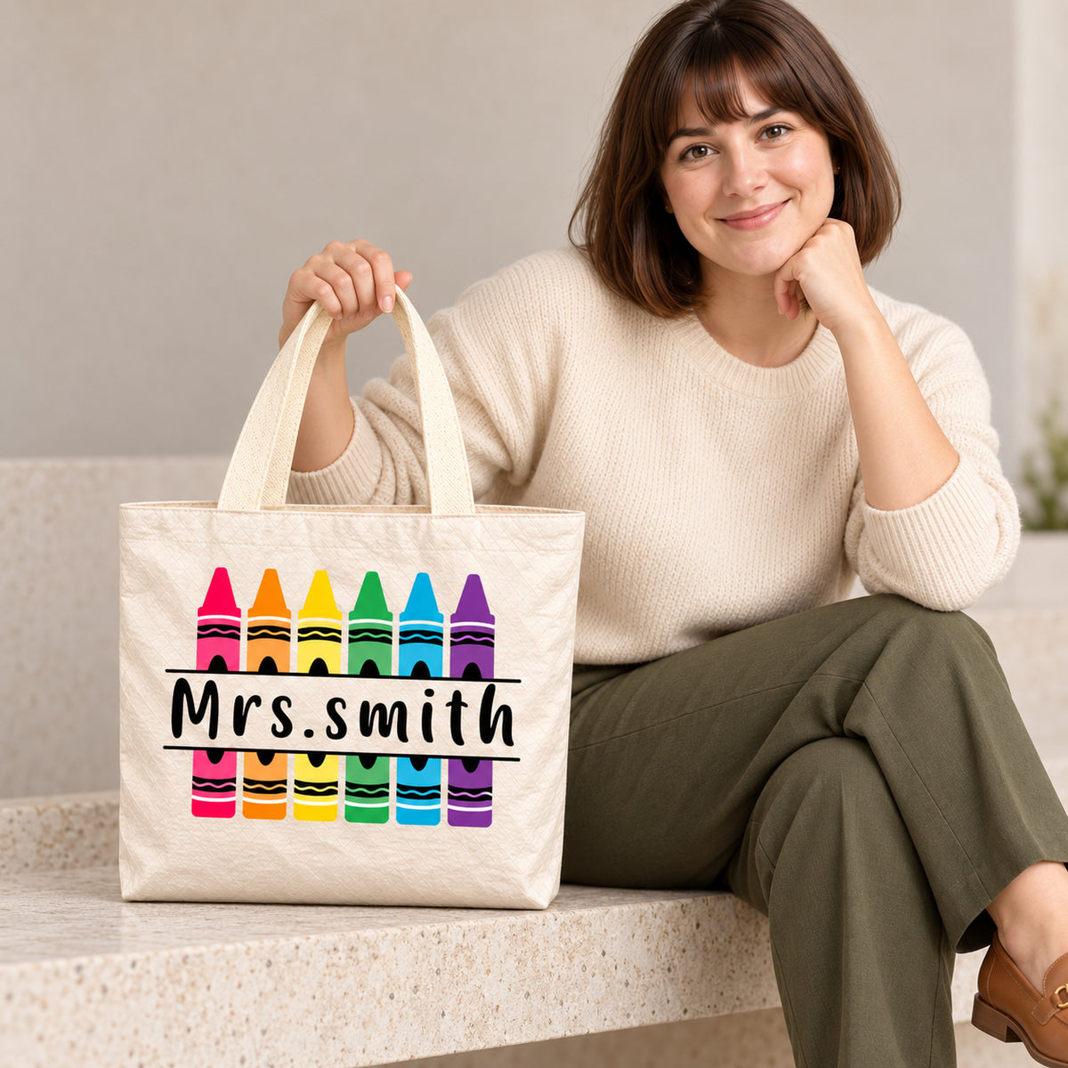 Personalized rainbow crayon teacher tote bag with custom name, showing the crinkled paper-like surface and handles.