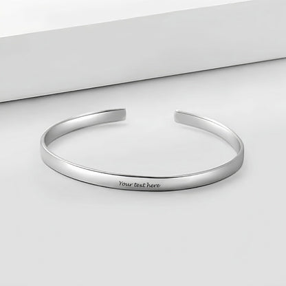 Personalized sterling silver cuff bracelet flat lay. Custom engraved text for men.