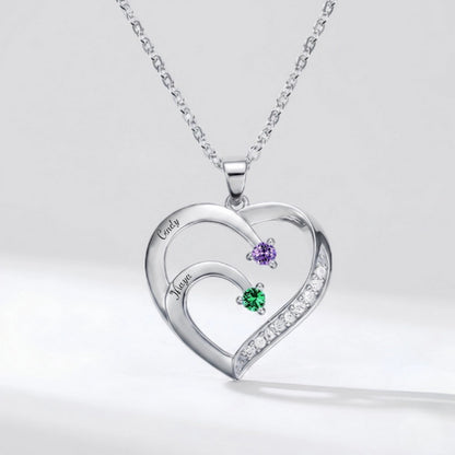 Silver heart necklace engraved with two names and stones.