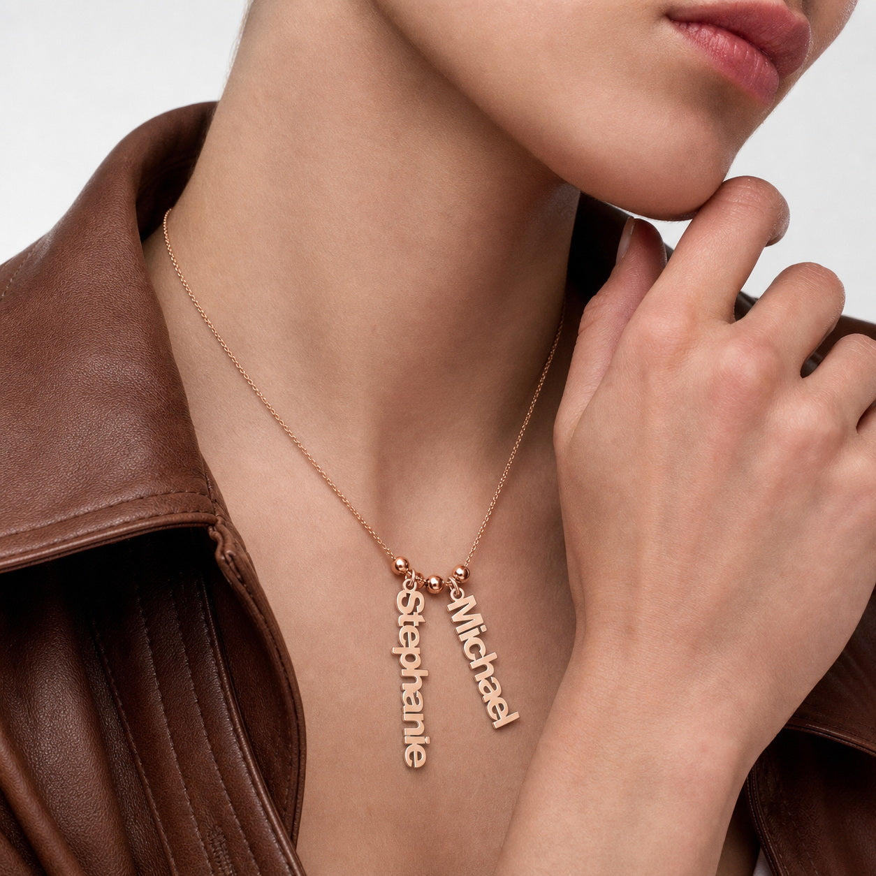Woman wearing a custom two name charm necklace in rose gold