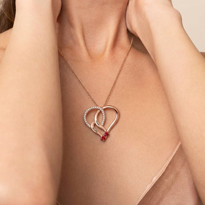 Woman wearing a rose gold heart necklace with two names.