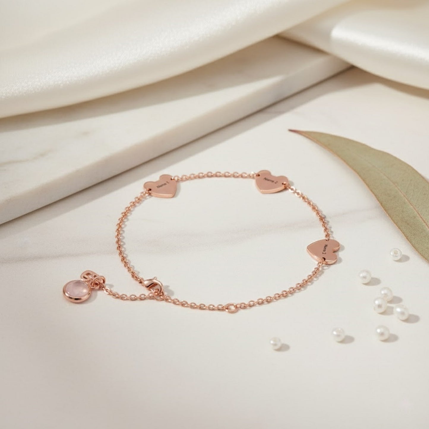 Rose gold personalized hearts charm bracelet with custom name hearts and a pink birthstone on a clean white background.