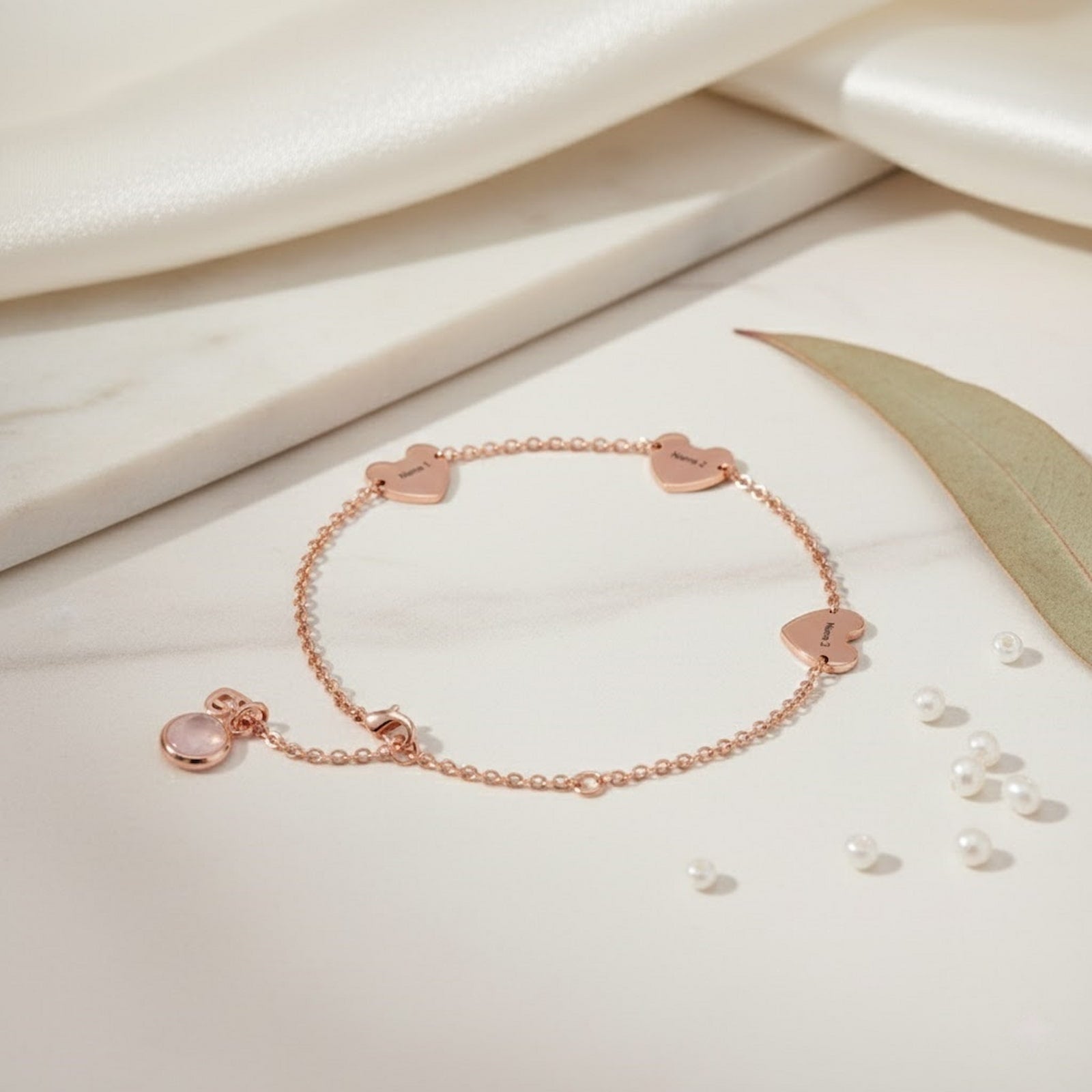 Rose gold personalized hearts charm bracelet with custom name hearts and a pink birthstone on a clean white background.
