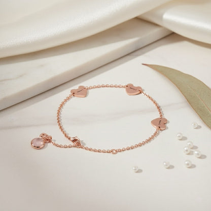 Rose gold personalized hearts charm bracelet with custom name hearts and a pink birthstone on a clean white background.
