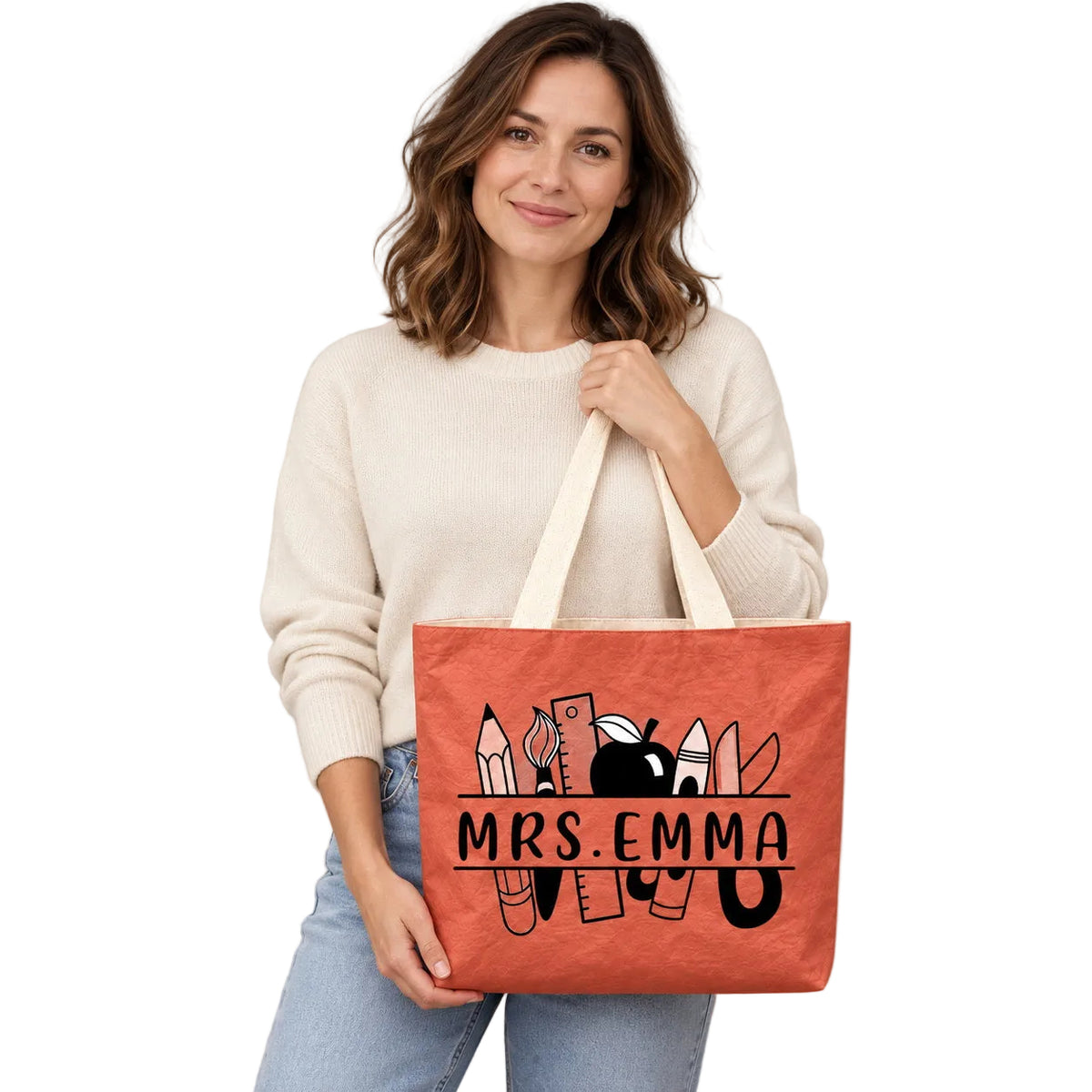 Personalized teacher tote with school supplies artwork and custom name MRS.EMMA, hero view.