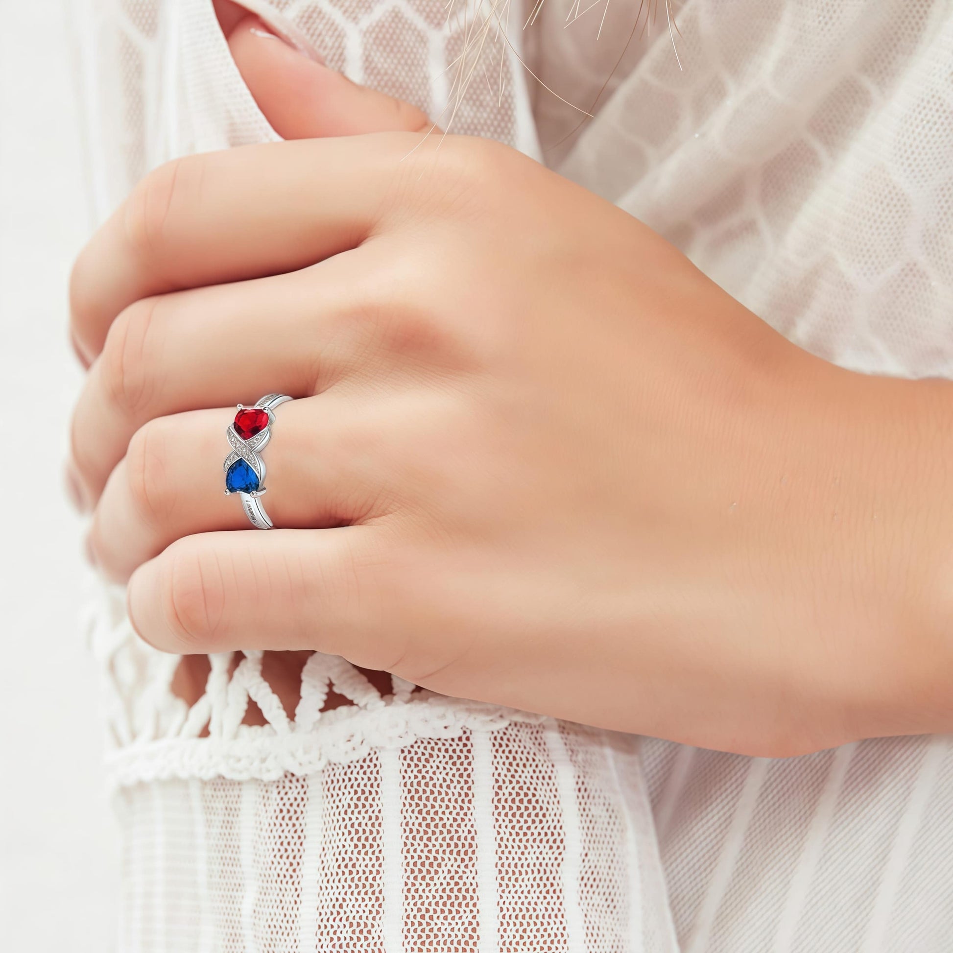 Hand model wearing the personalized Sterling Silver promise ring with red and blue stones.