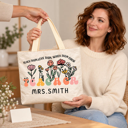 Personalized teacher tote with floral teacher artwork with the phrase TEACH THEM, LOVE THEM, WATCH THEM GROW and custom name MRS.SMITH, teacher appreciation gift view.