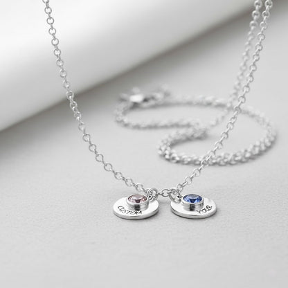 Two custom birthstone disc necklaces with personalized text in sterling silver.