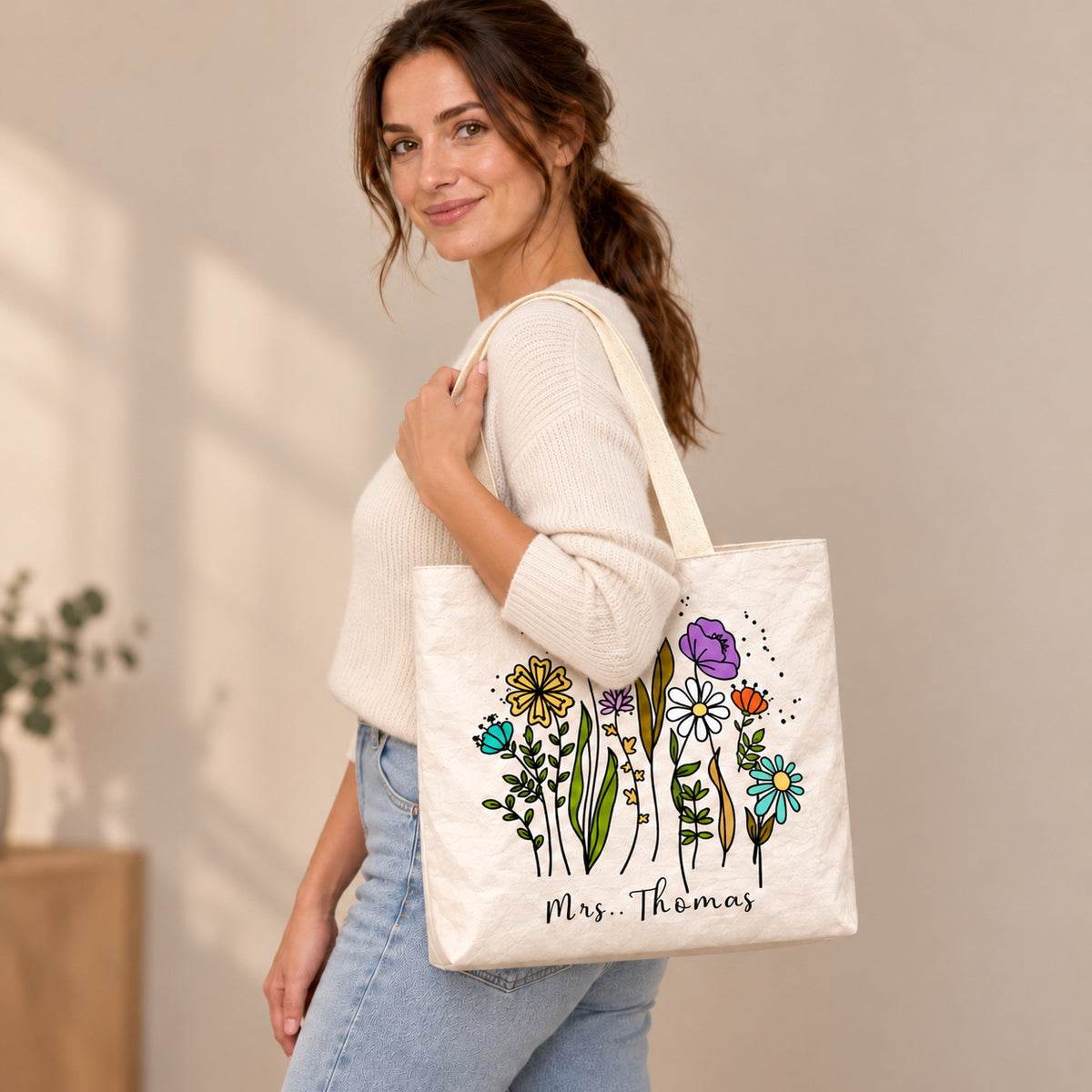 Personalized teacher tote with colorful wildflower artwork and custom name Mrs. Thomas, shoulder side view view.