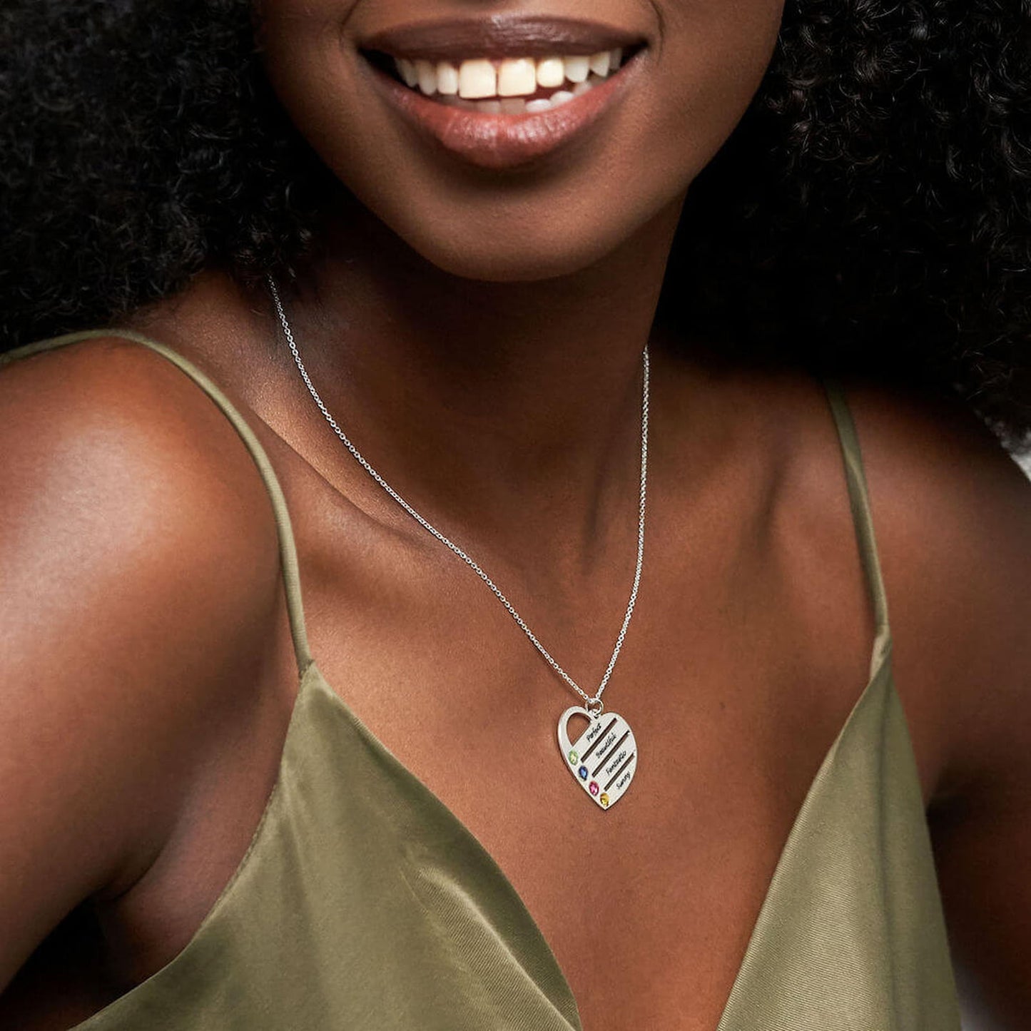 Woman smiling, wearing personalized sterling silver heart family necklace.