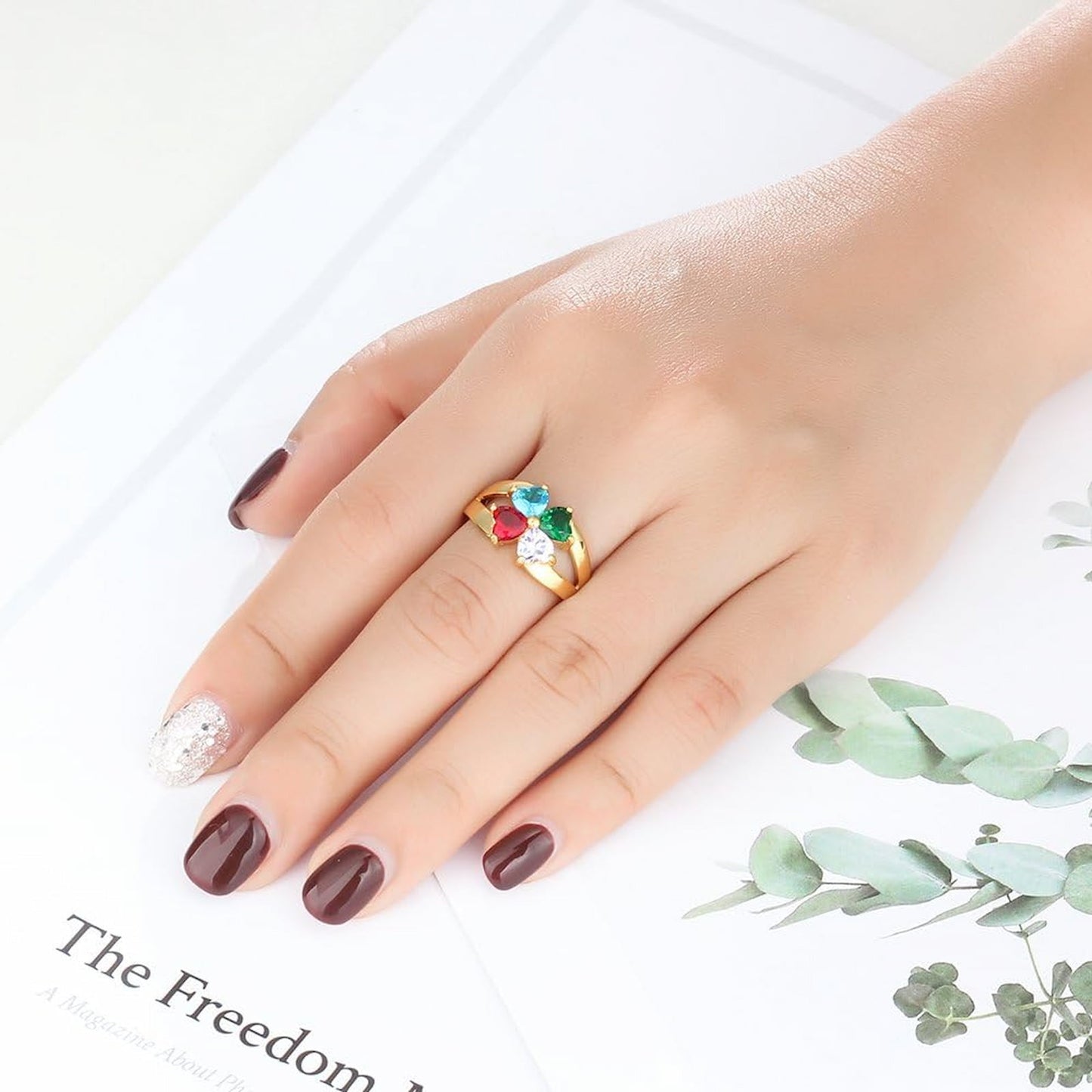 Woman wearing gold personalized heart birthstone ring on hand. Custom family gift for Mom.