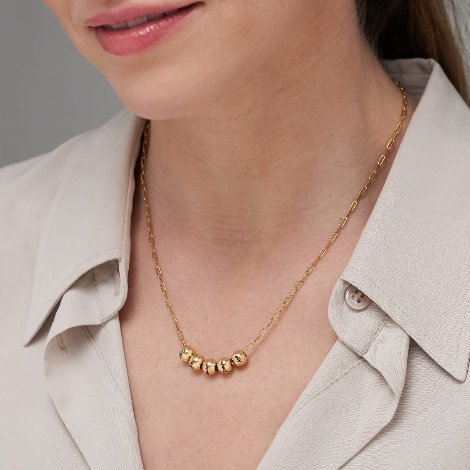 Woman wearing gold personalized name bead paperclip necklace. Custom engraved names.