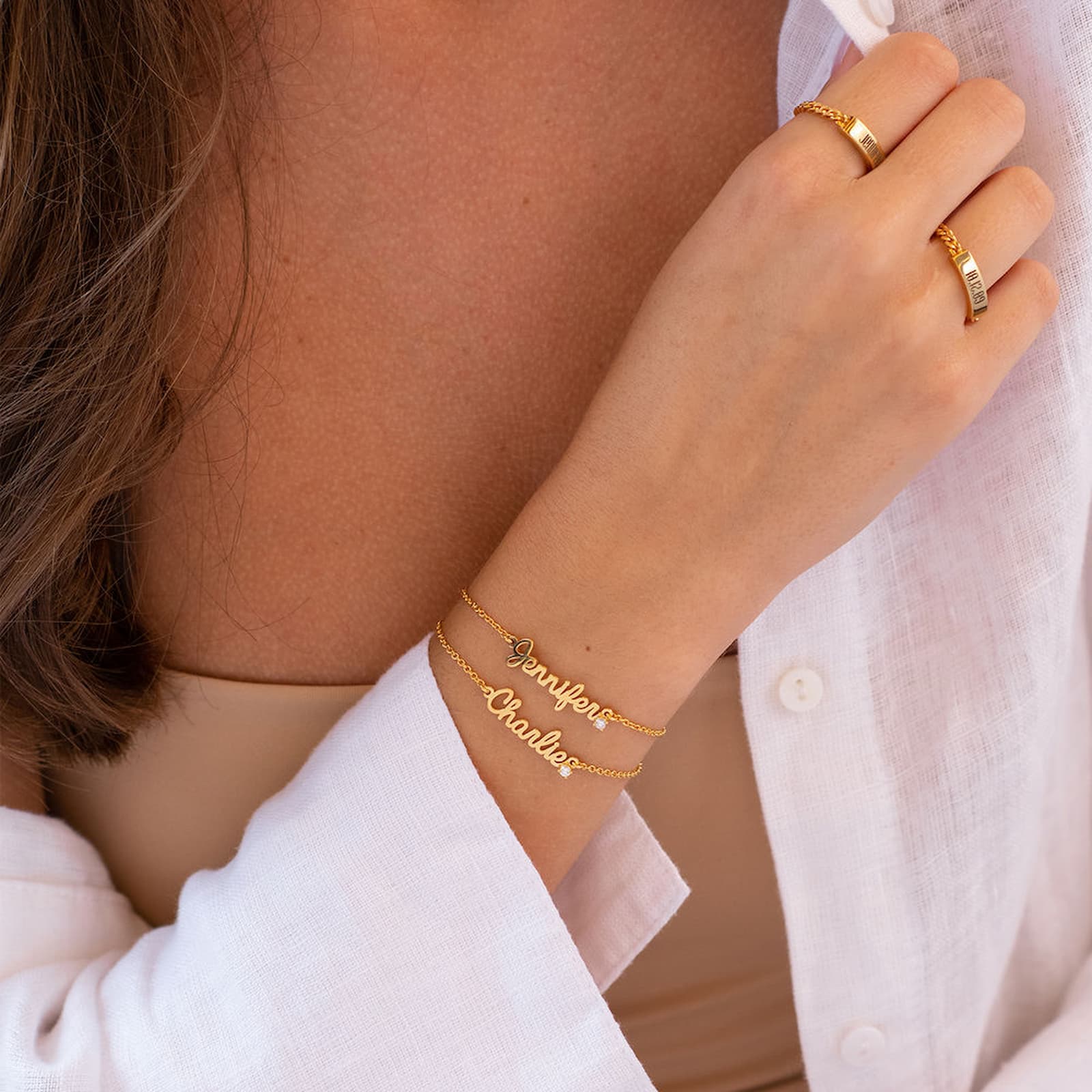 Woman wearing gold personalized name bracelet. 