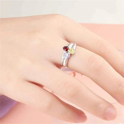 Woman wearing personalized 3 birthstone heart ring with custom names on finger.