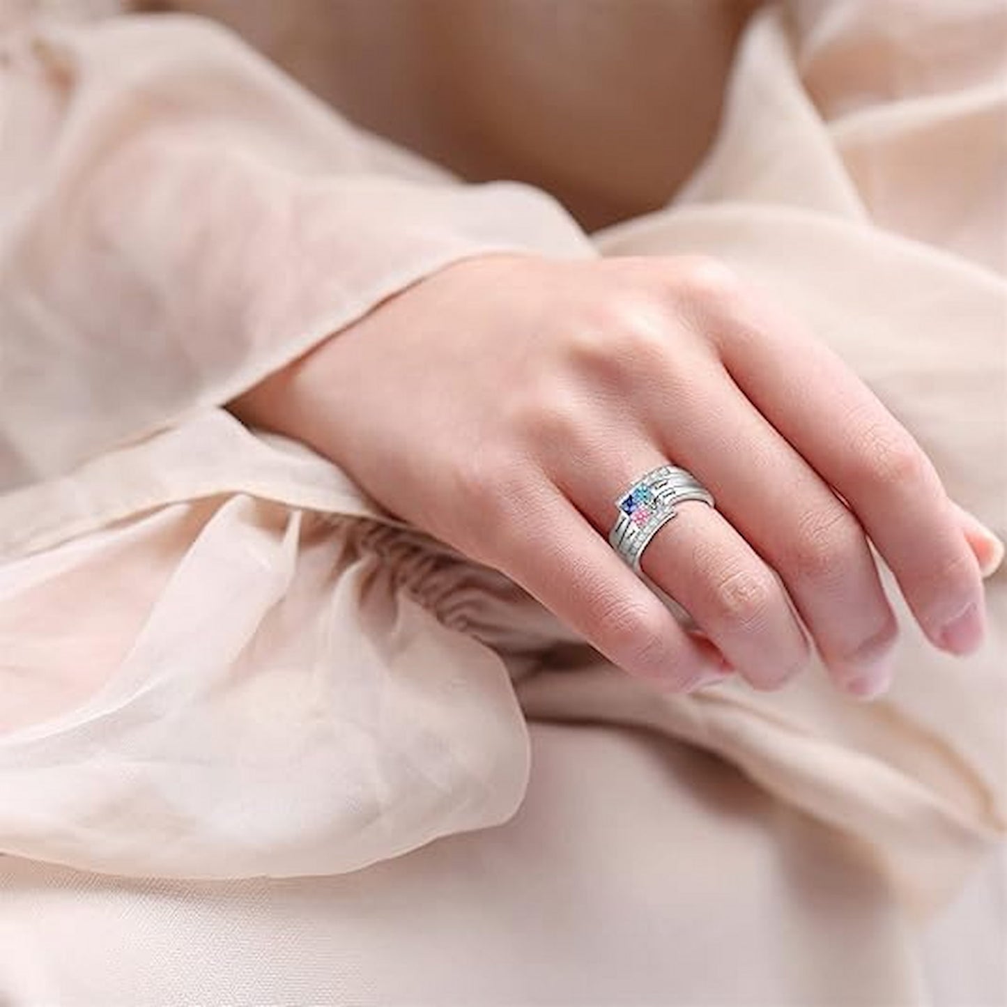 Close-up of woman wearing personalized sterling silver family birthstone ring on her hand. Custom names & stones.