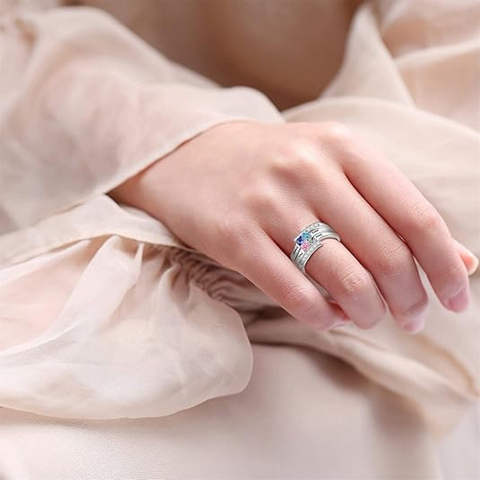 Close-up of woman wearing personalized sterling silver family birthstone ring on her hand. Custom names & stones.