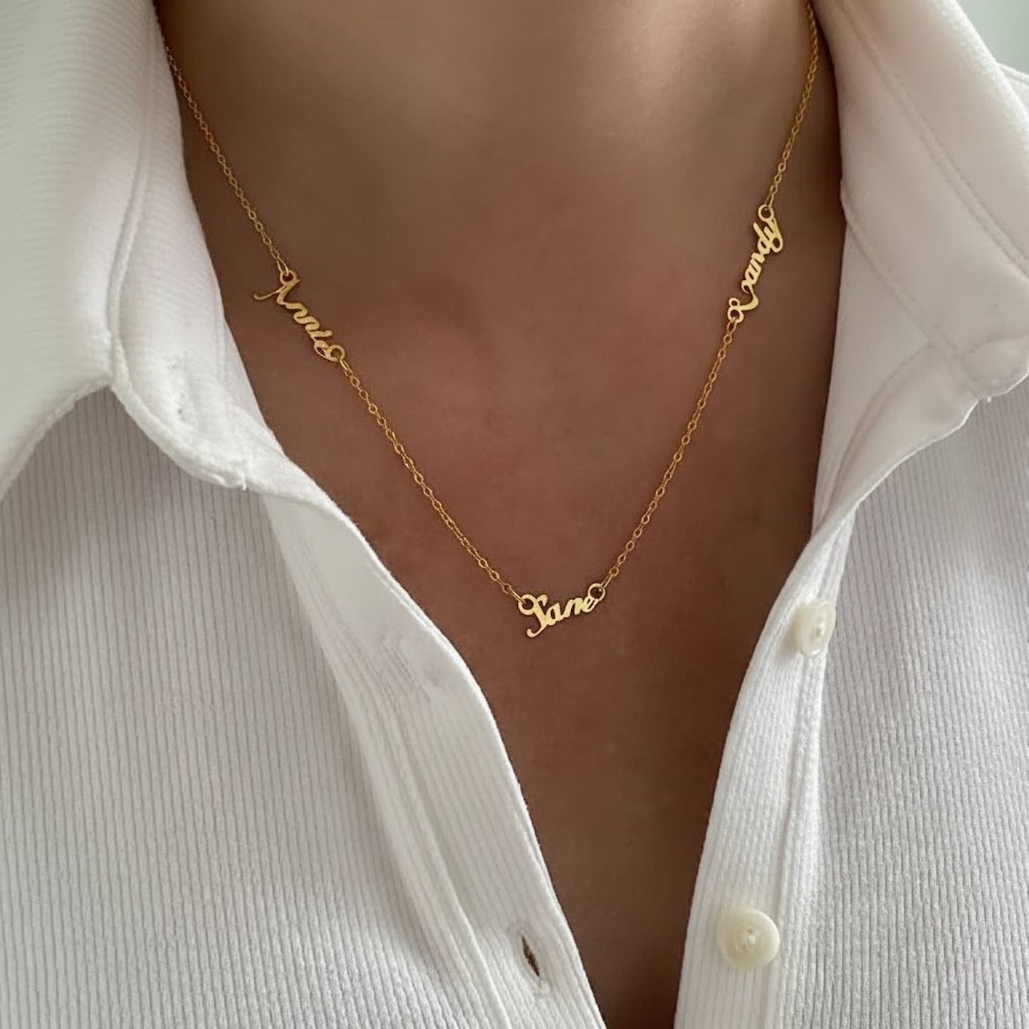 Close-up shot of a woman wearing a personalized gold multiple name necklace, clearly showing the custom names.
