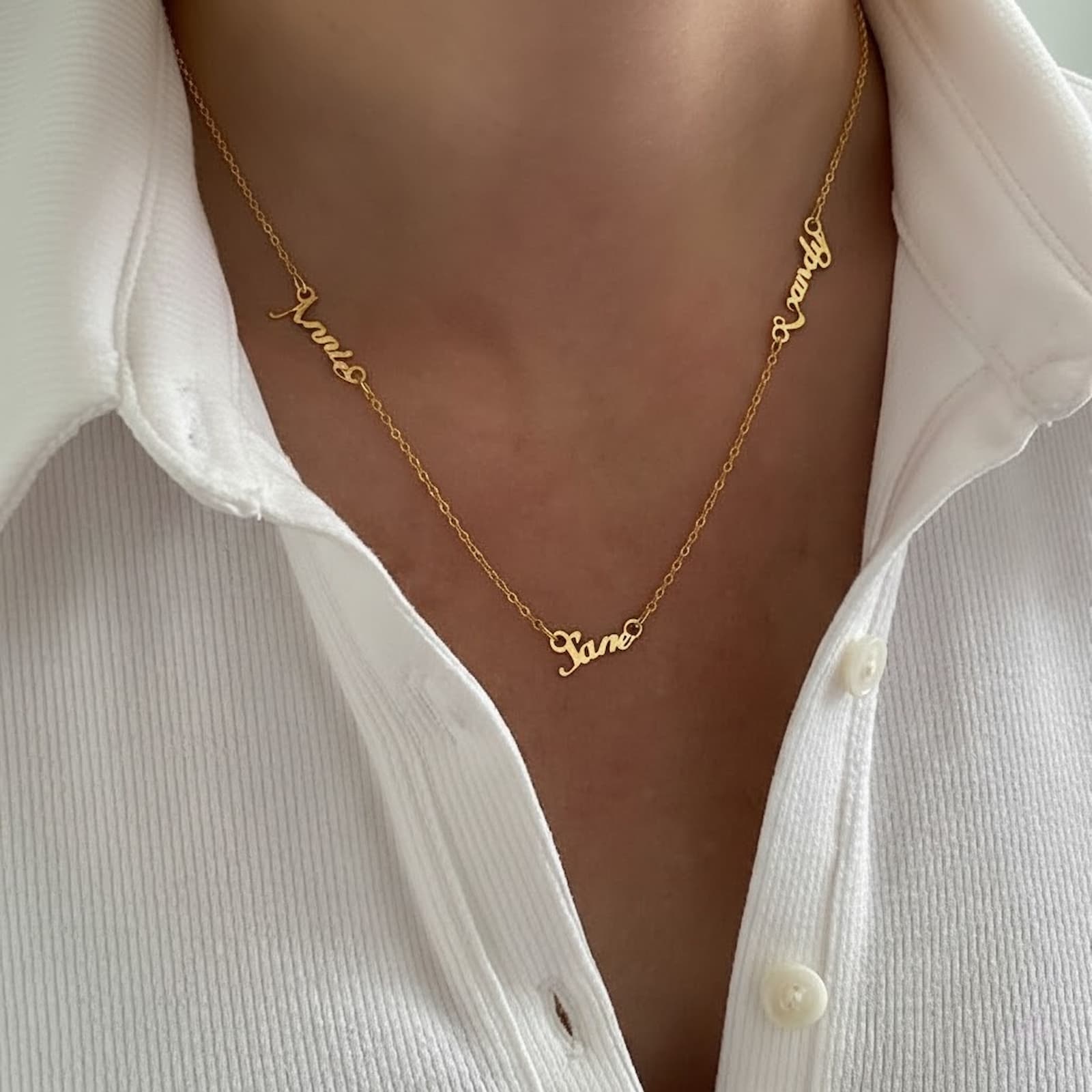 Close-up shot of a woman wearing a personalized gold multiple name necklace, clearly showing the custom names.
