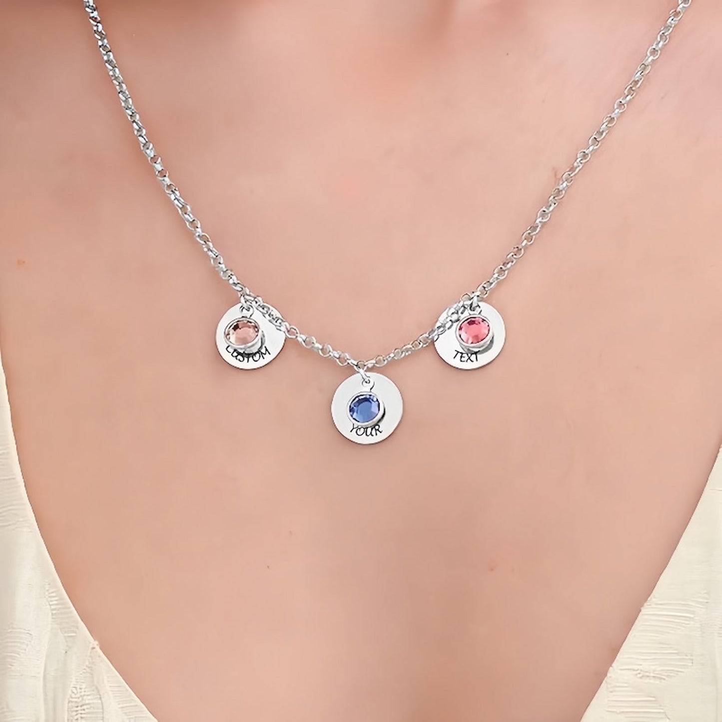 Model wearing rose gold multi-charm engraved necklace with birthstones and text.