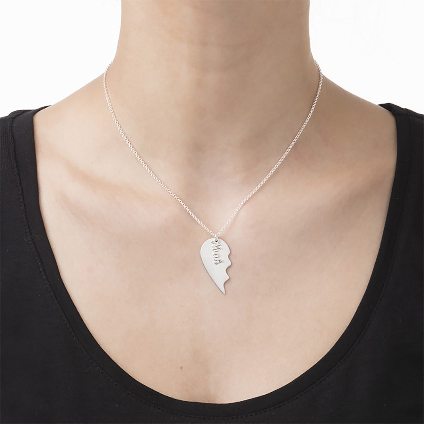 Woman wearing personalized silver half heart name necklace, part of a BFF set.