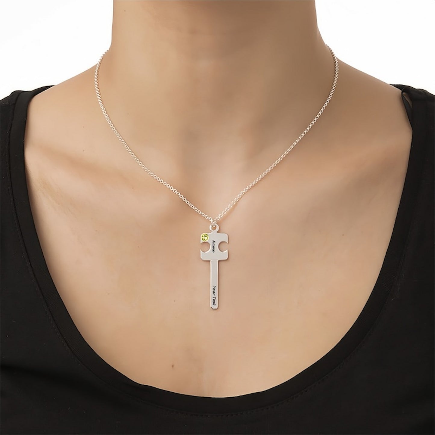 Woman wearing personalized sterling silver puzzle key necklace with custom name, text, and green simulated birthstone. Matching couple gift.