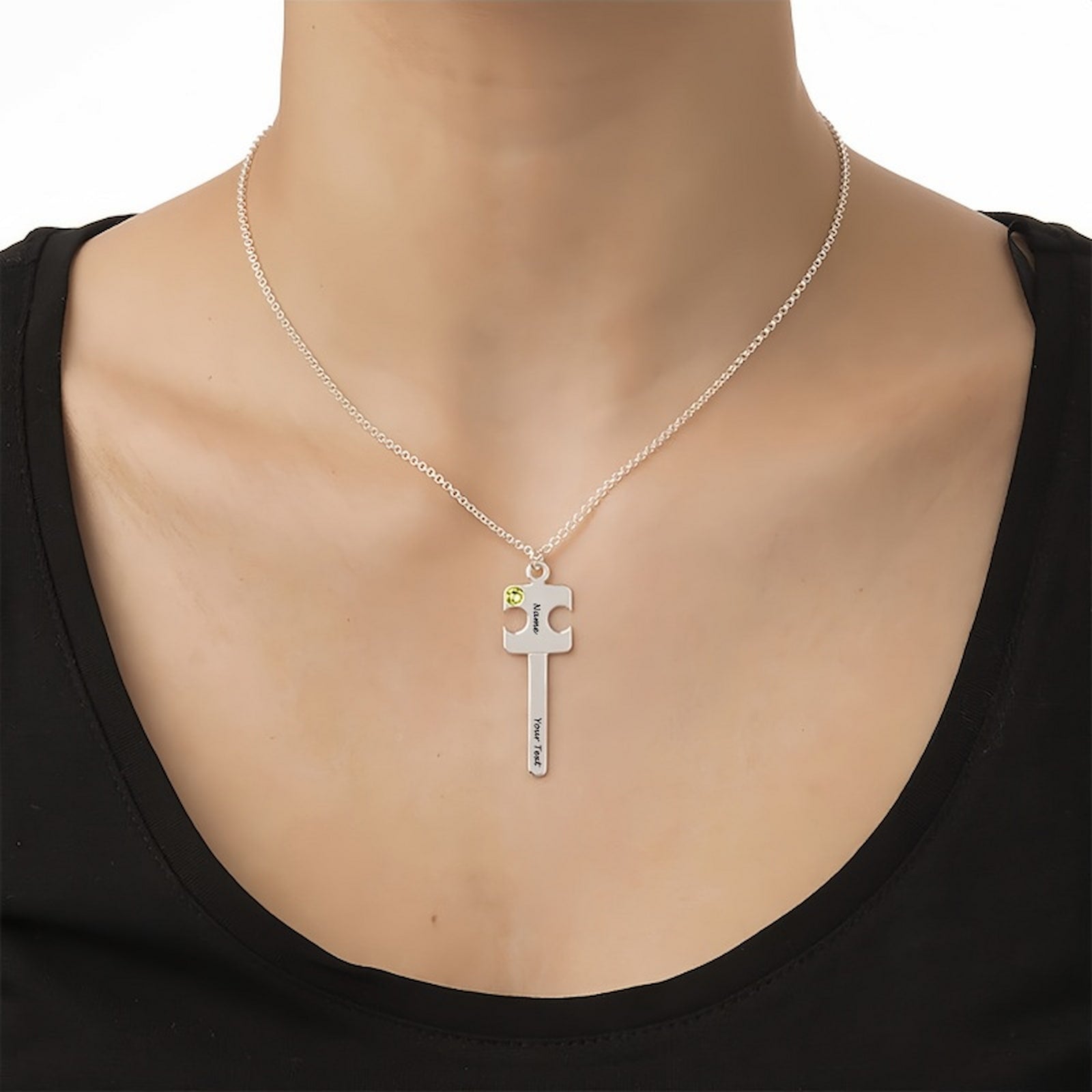 Woman wearing personalized sterling silver puzzle key necklace with custom name, text, and green simulated birthstone. Matching couple gift.