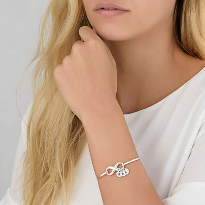 Woman wearing silver infinity initial bangle bracelet. Personalized with engraved letters.